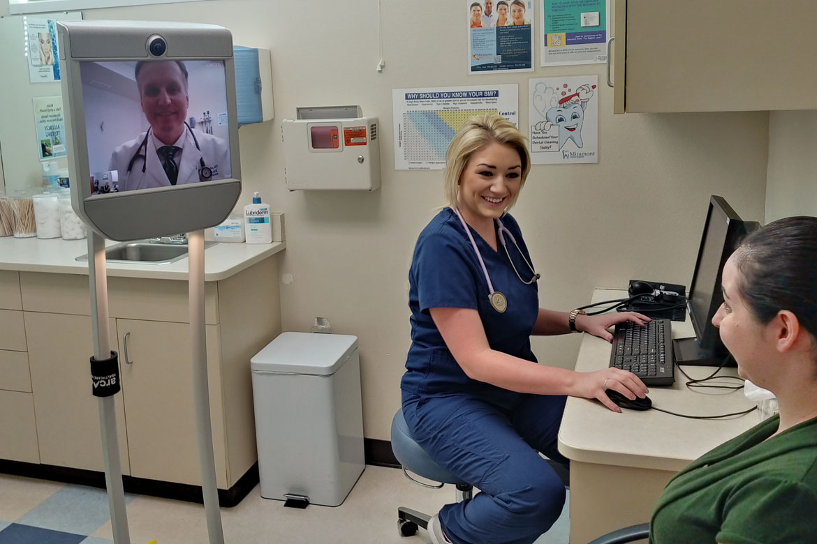 Doctor tele-consulting patient with nurse attending