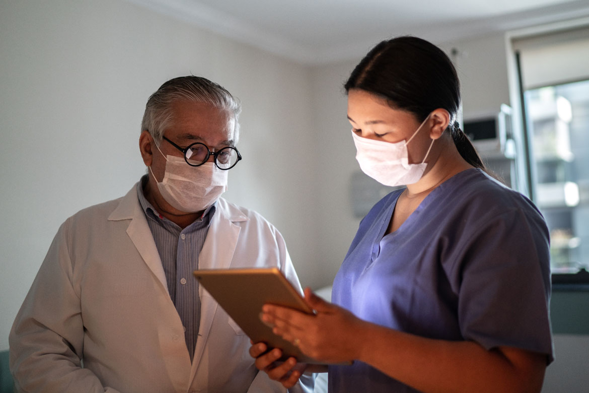 Physician and assistant looking at tablet