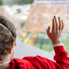 A pediatric patient waves back to fans and players during the Hawkeye Wave