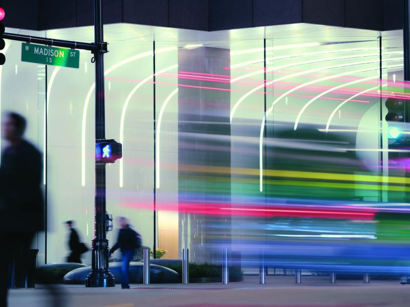 Businesspeople and traffic passing illuminated office facade