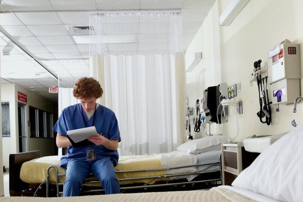 A resident studies his notes in an empty hospital room. 