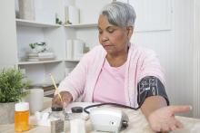 Woman recording her blood pressure at home
