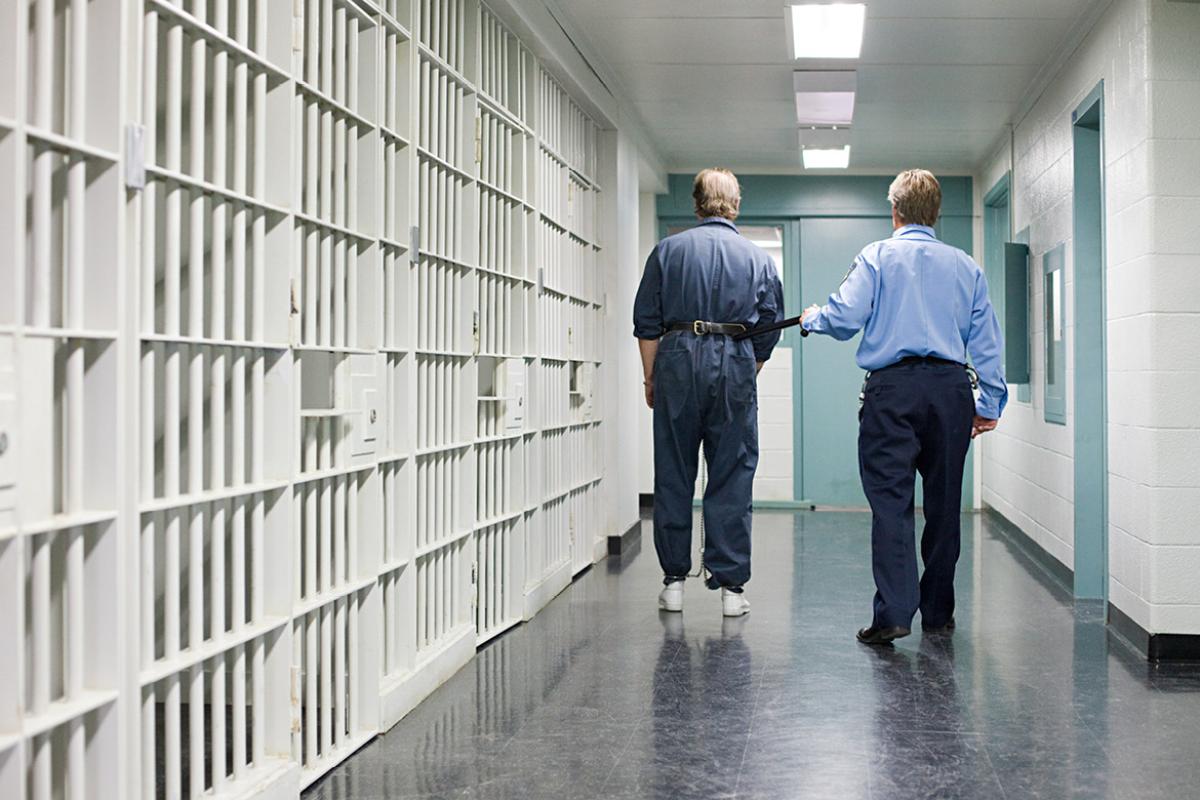 Officer escorts prisoner down hallway to cell.