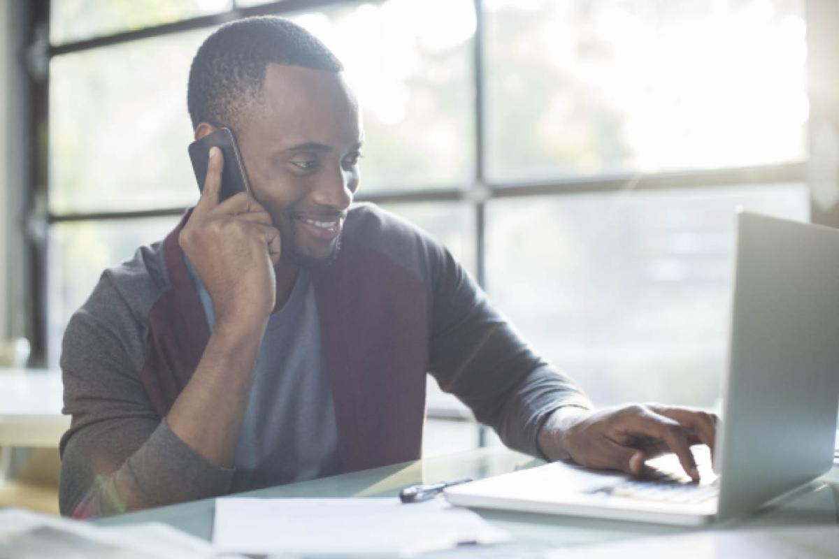 Man in front of computer, interviewing on phone 