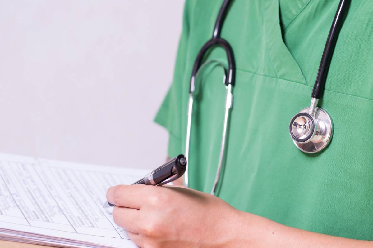 A doctor in scrubs, making notes