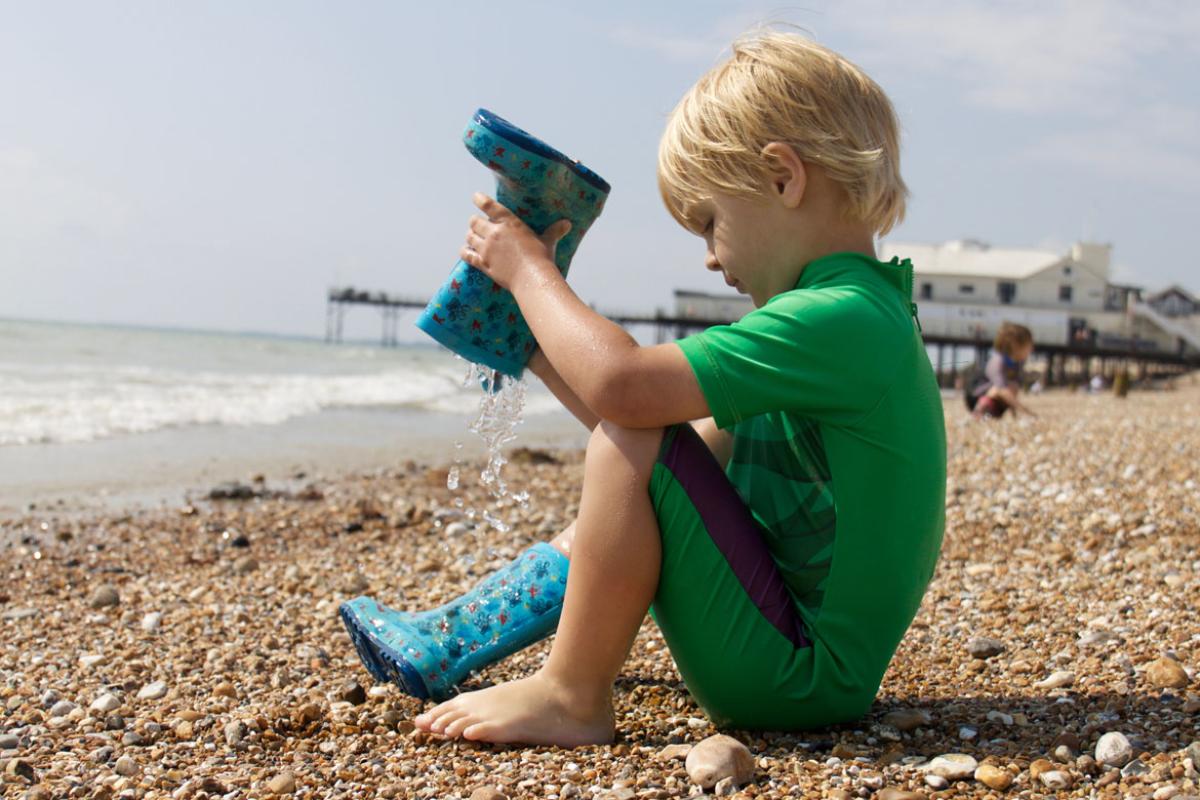 Child removing pebbles from a boot