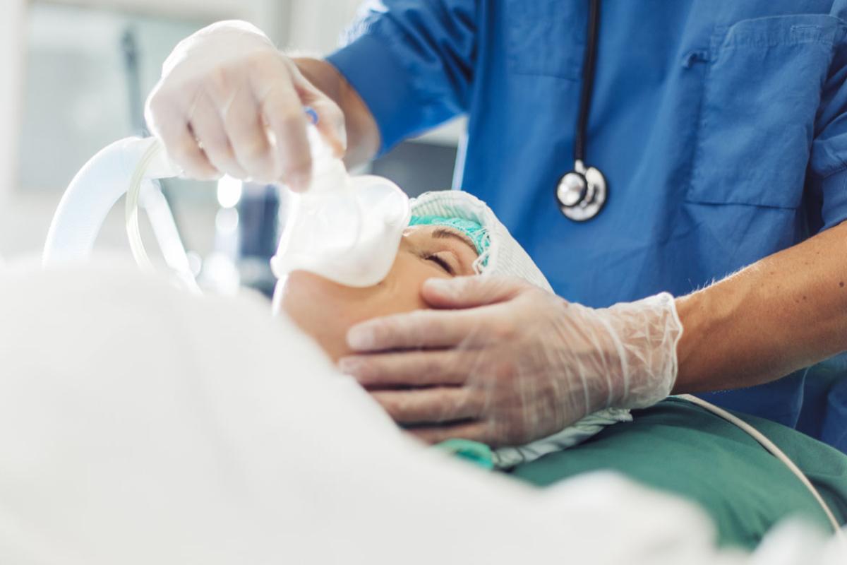 A health care worker places a mask over a patient's mouth