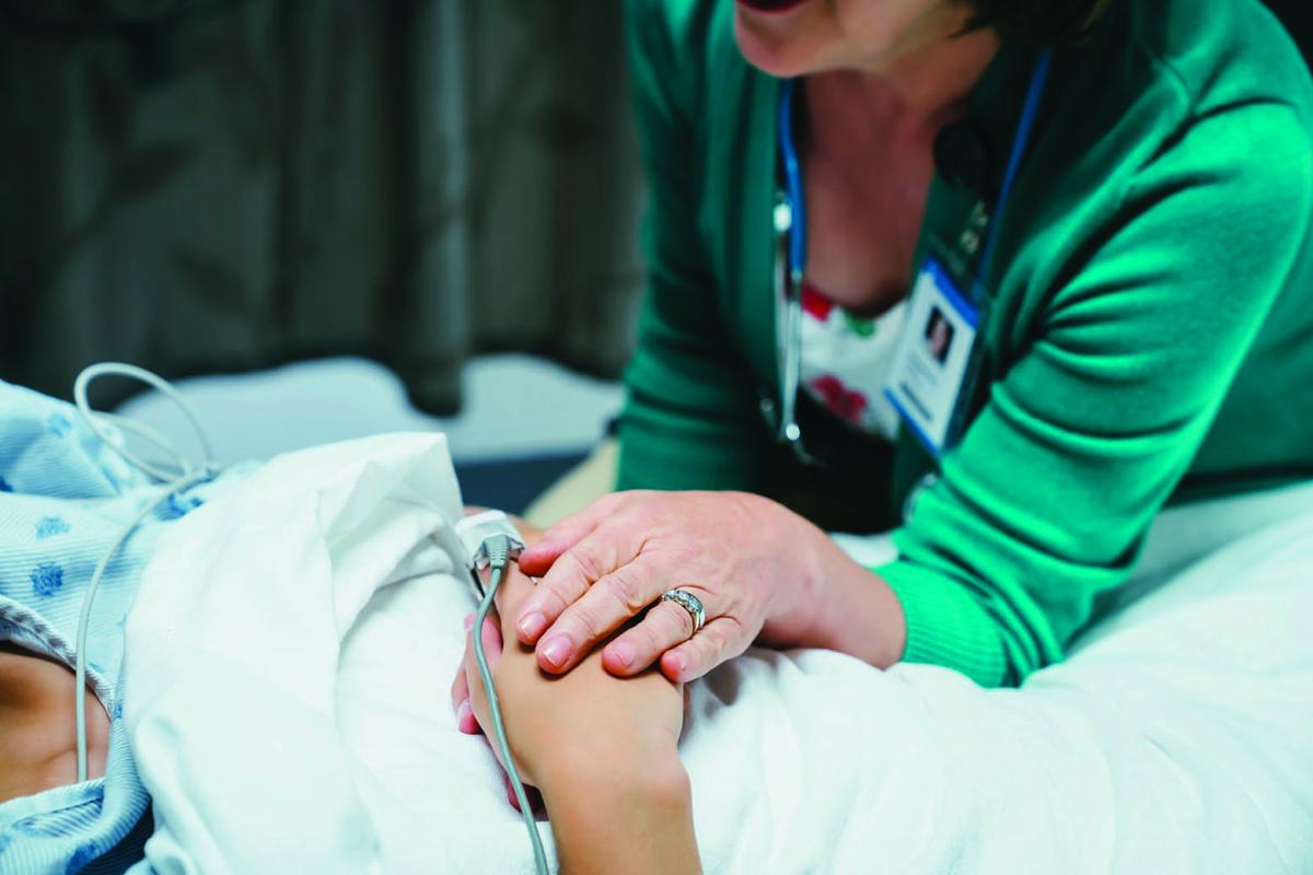 A woman's hand placed over the hand of a patient