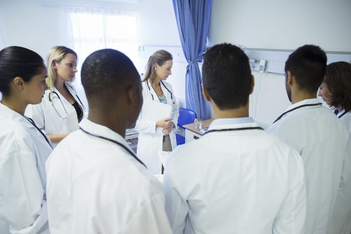 Physicians standing around a hospital bed