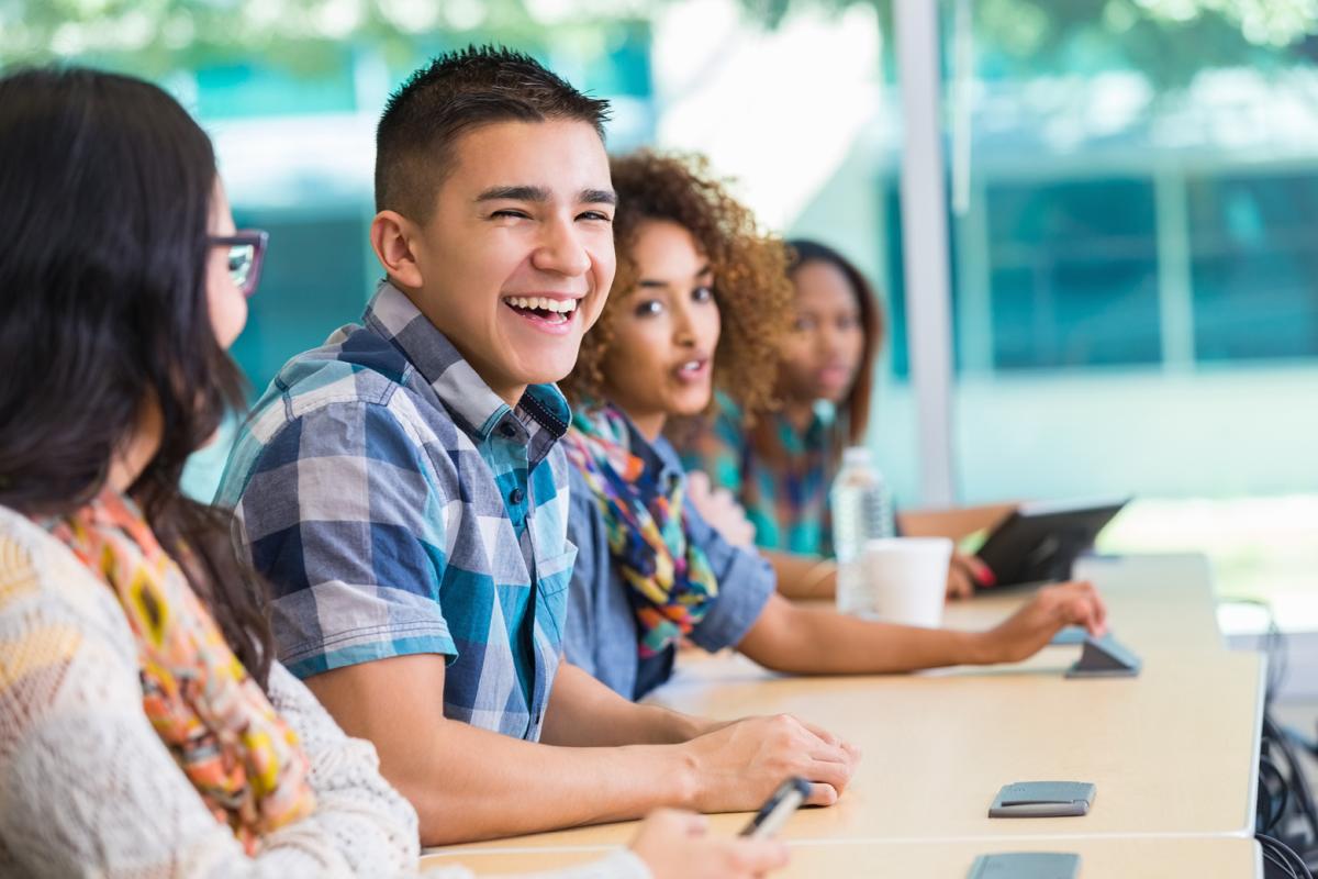 Four smiling students sitting in class