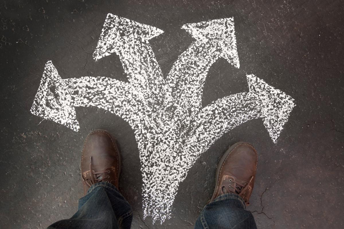 A person looking at four chalk arrows drawn on the ground