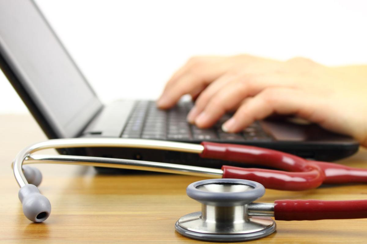 Stethoscope next to a physician working on a computer