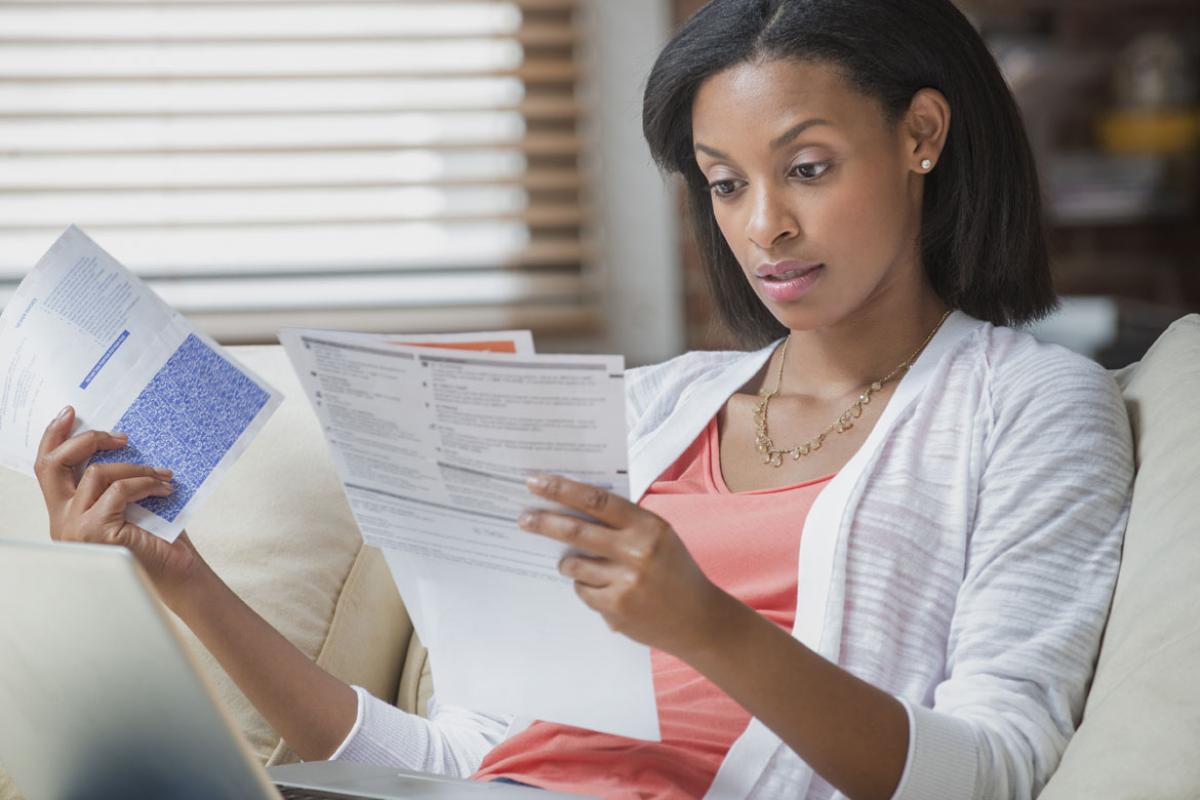 Woman sitting on couch looking at bills