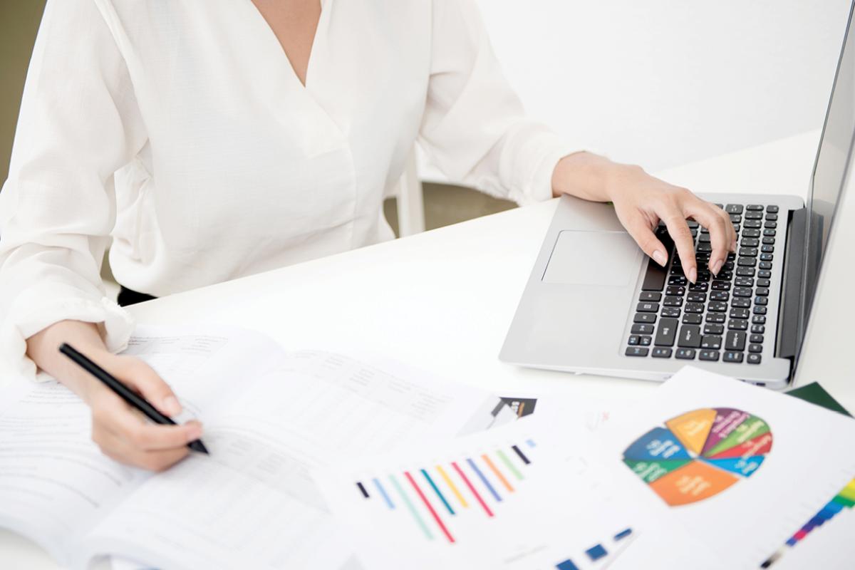 Woman at a desk with a laptop and bar charts