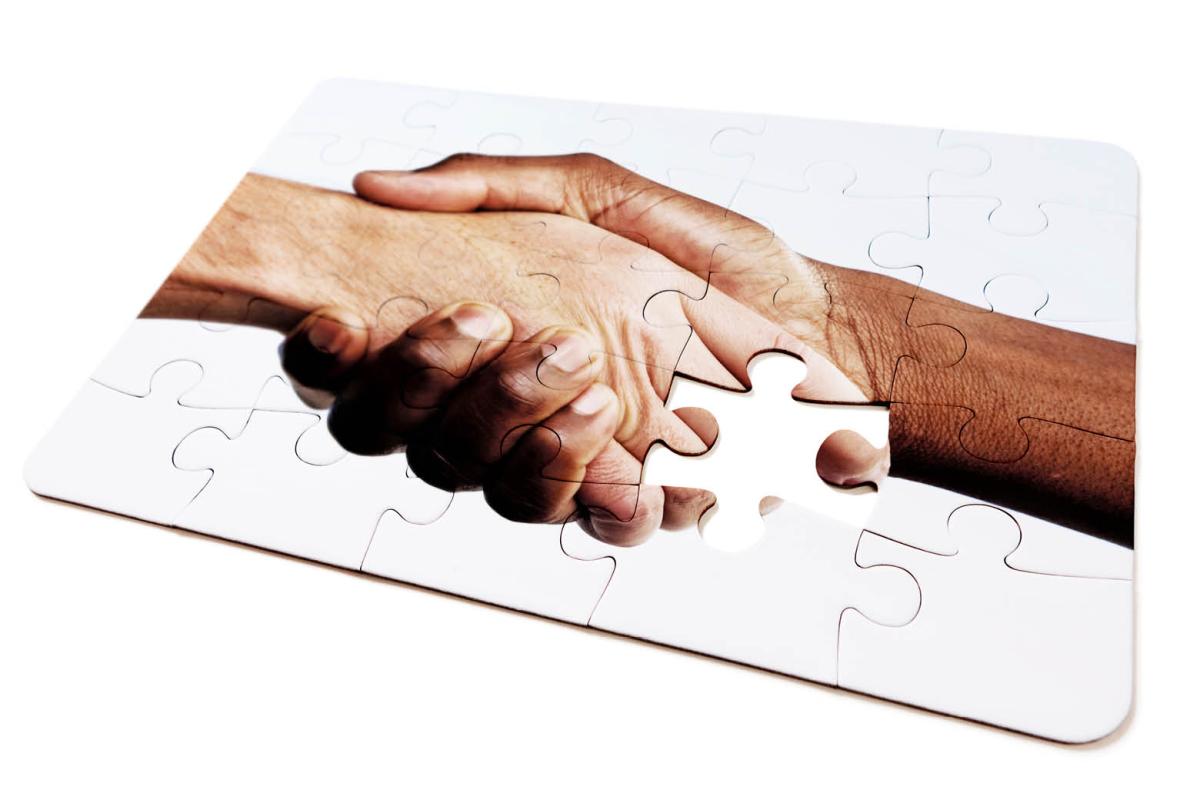 Puzzle of two hands shaking with one puzzle piece missing