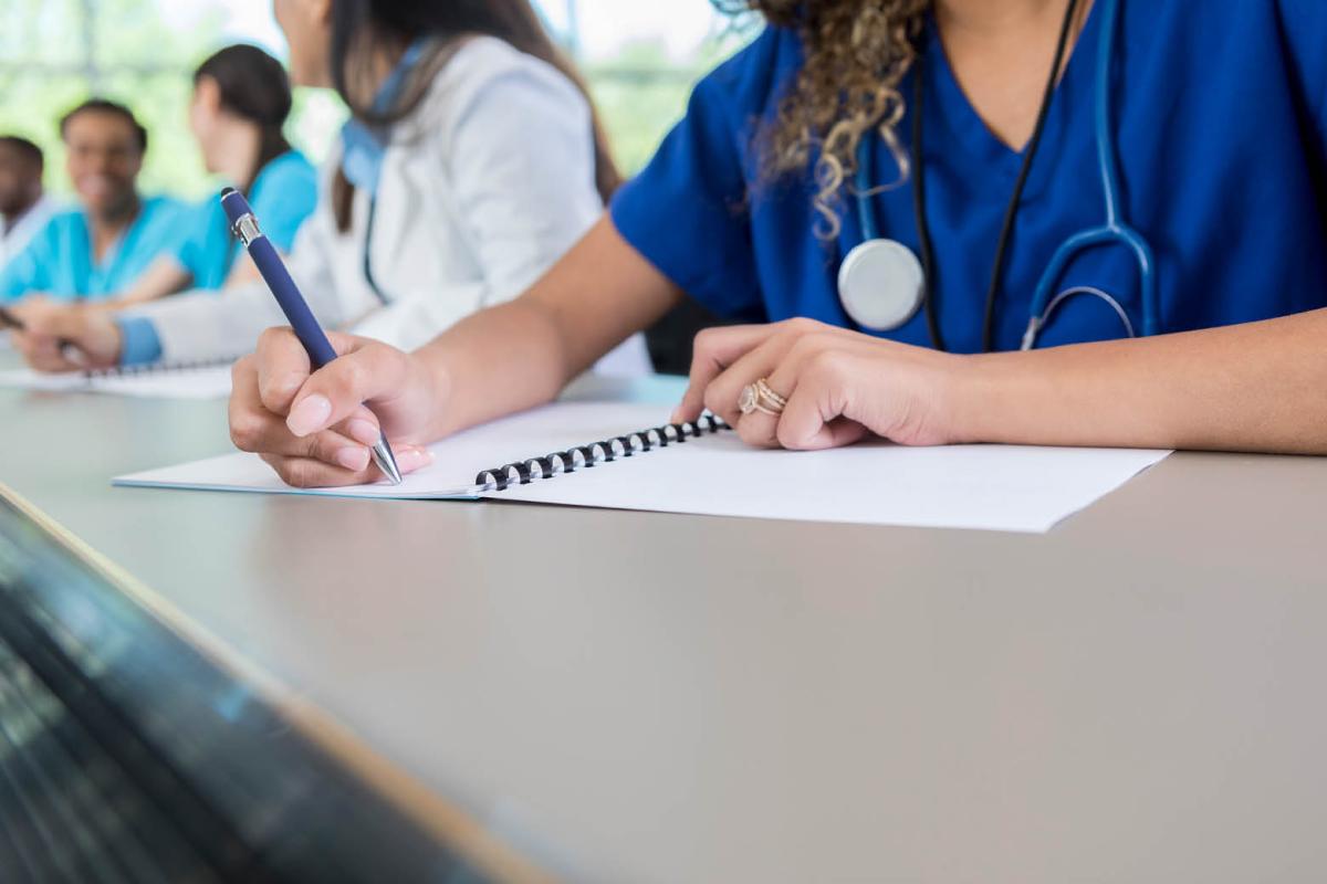 Woman in scrubs writing on a notebook