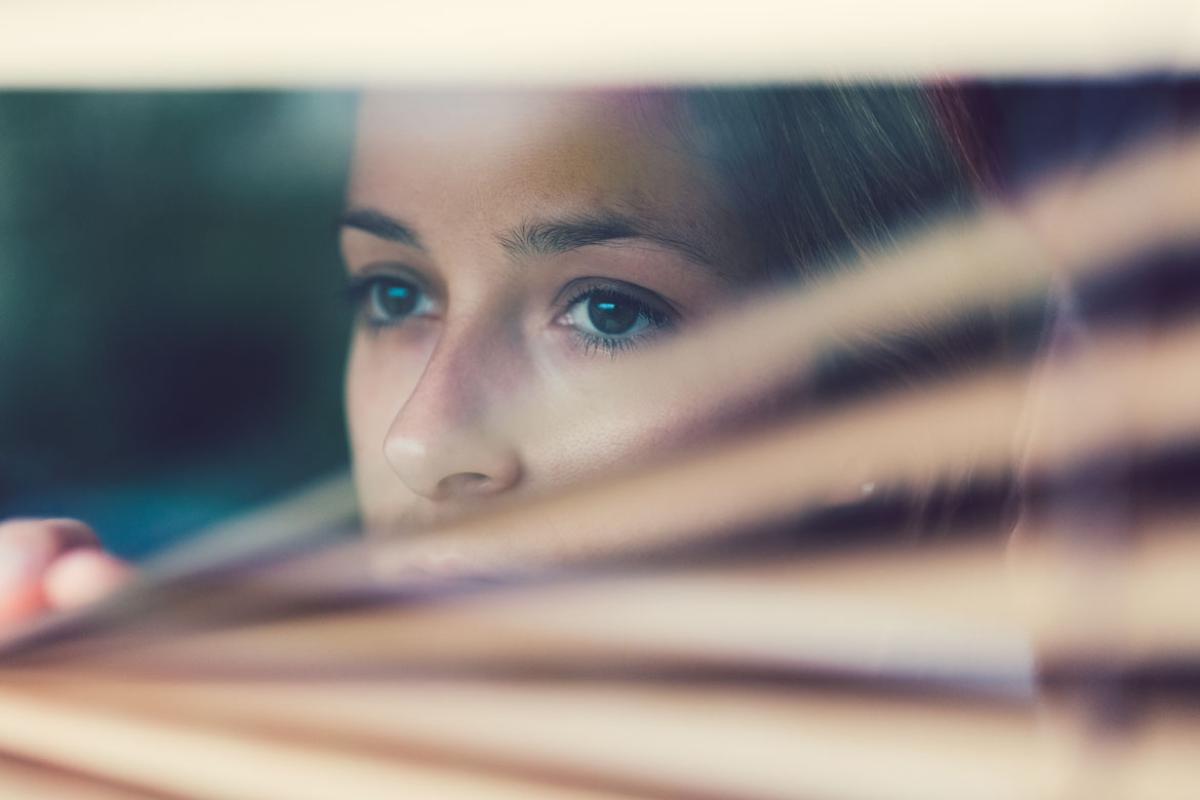 Woman looking through blinds