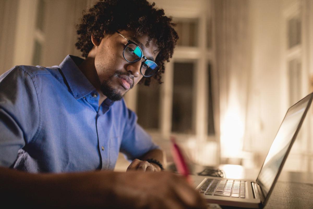 Young man writing near a laptop
