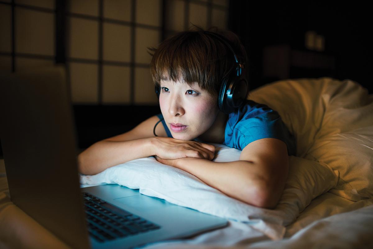 Woman in bed looking at a laptop