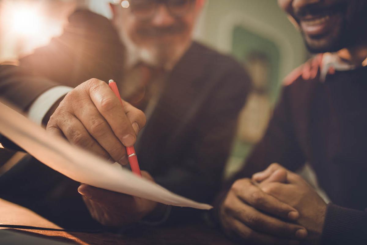 Man showing another man a paper or document to sign
