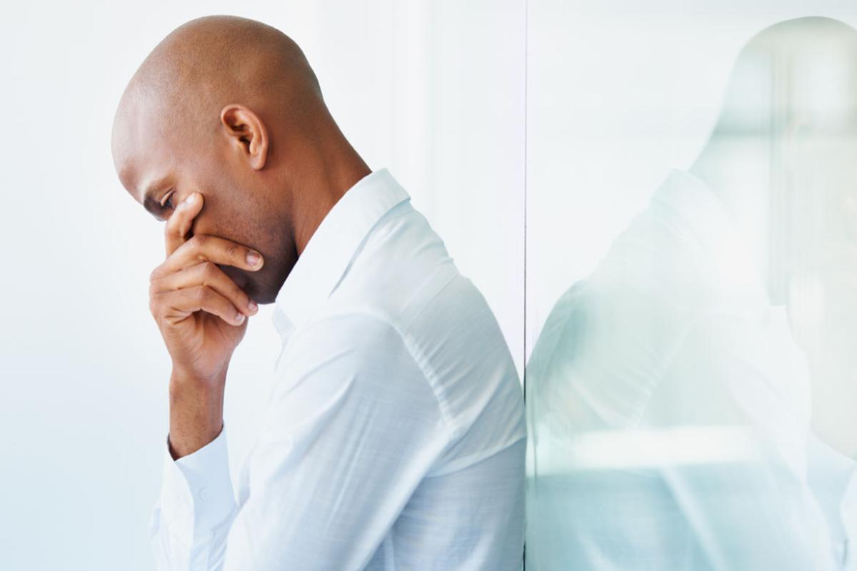 Man leaning against a wall with head in hand