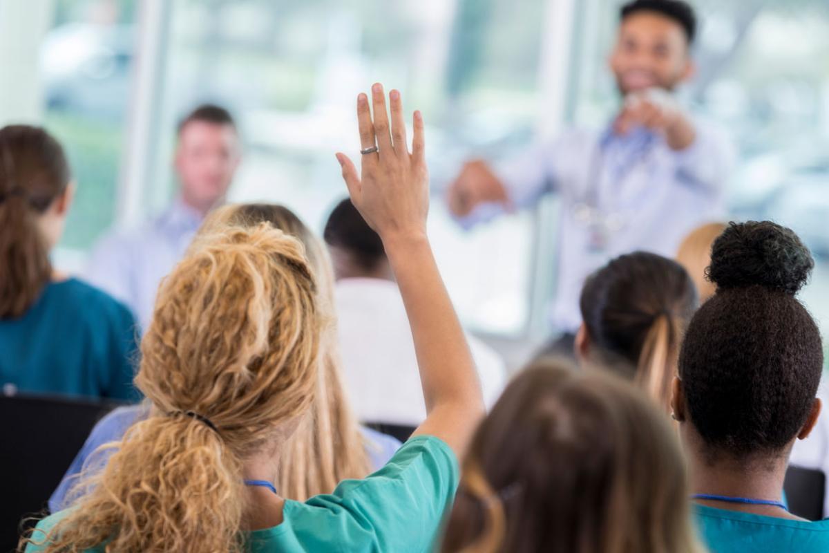 Physician raising hand in a group setting