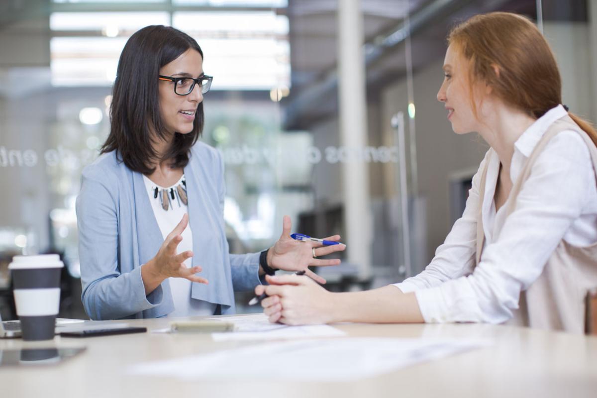Two young professionals speaking with one another