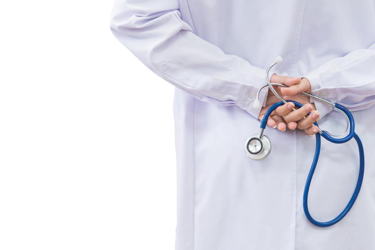 Physician holding stethoscope behind back