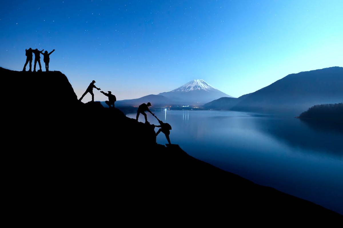 Silhouette of team climbing a mountain