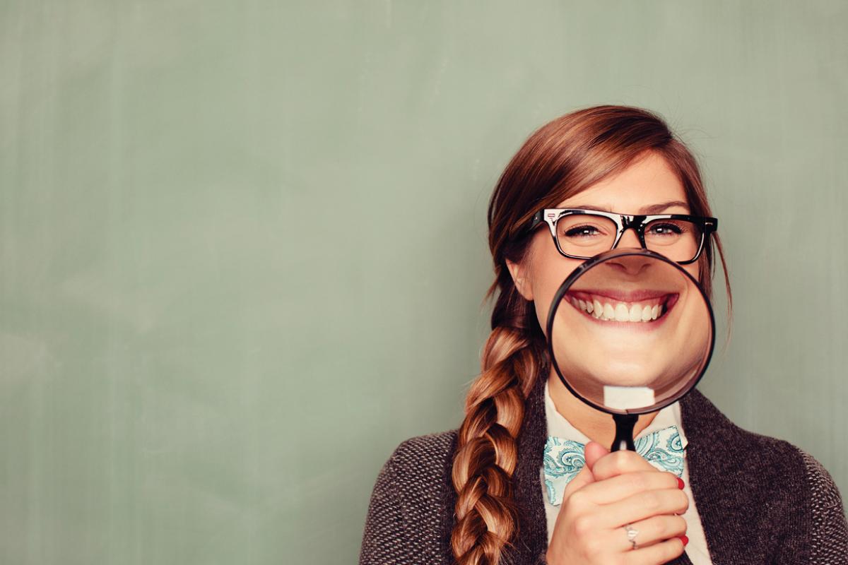 Woman smiling behind magnifying glass