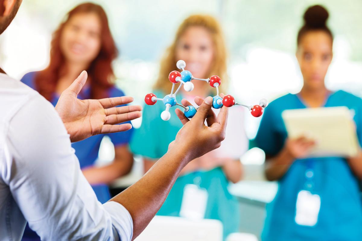 Man holding an atom model to teach residents