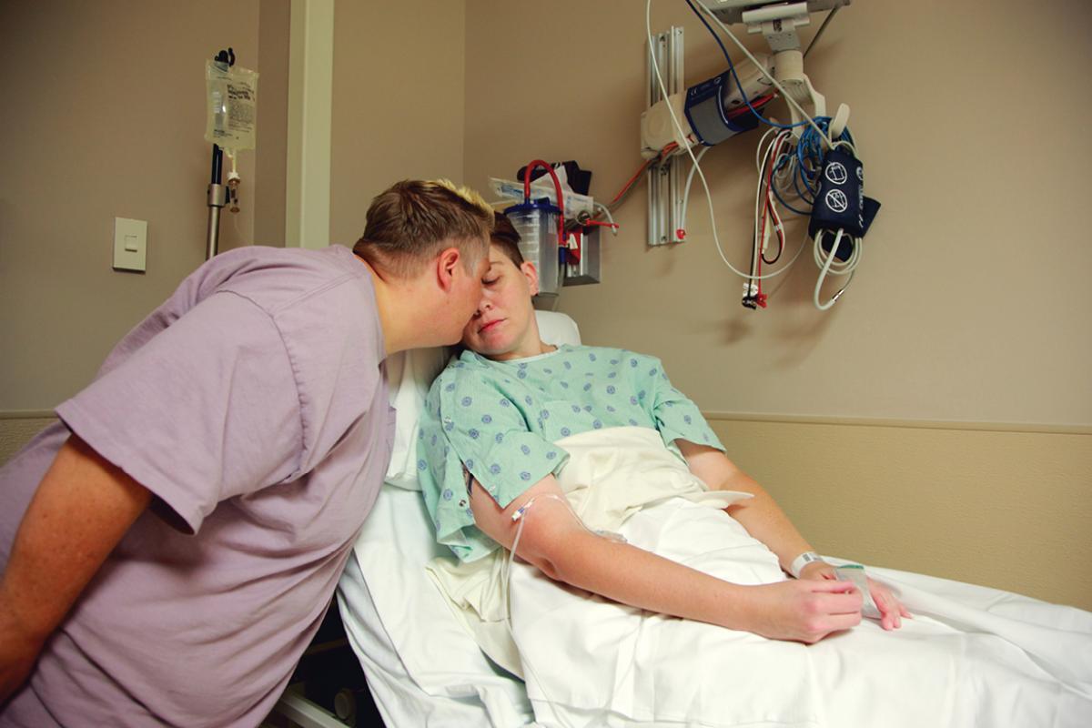 Patient on hospital stretcher being comforted by another person