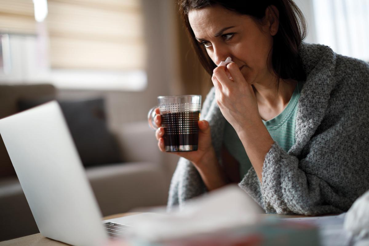 Woman in front of a laptop holding a tissue