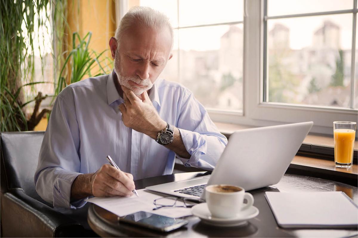 Man sitting in front of a laptop and writing a list