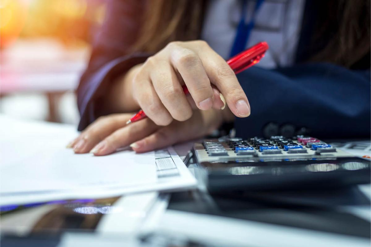 Person holding a pen and working with a calculator