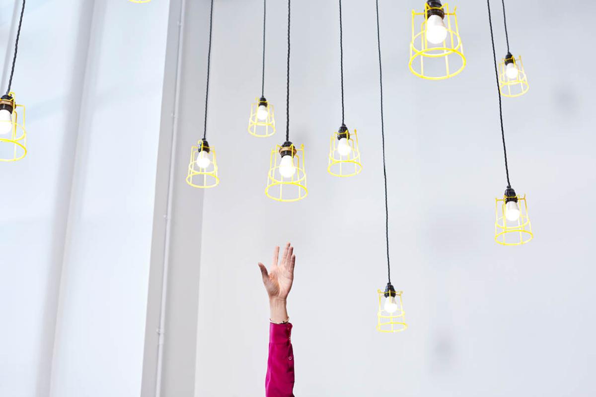 Hand reaching up toward hanging lightbulbs