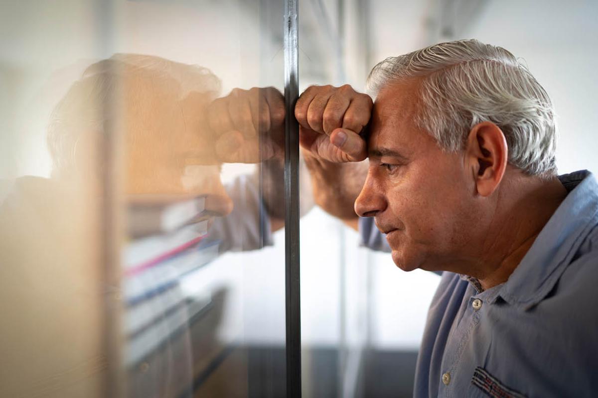Man leaning against a window with head in hand