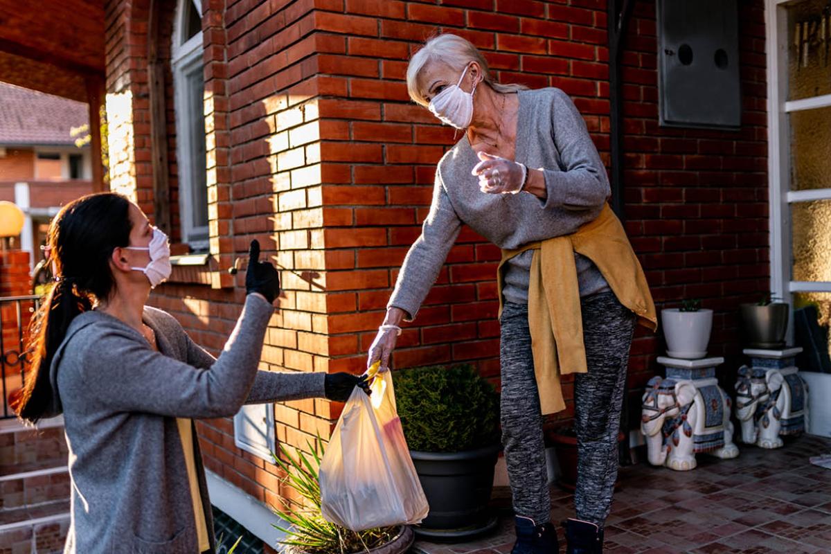 Woman handing groceries to another woman