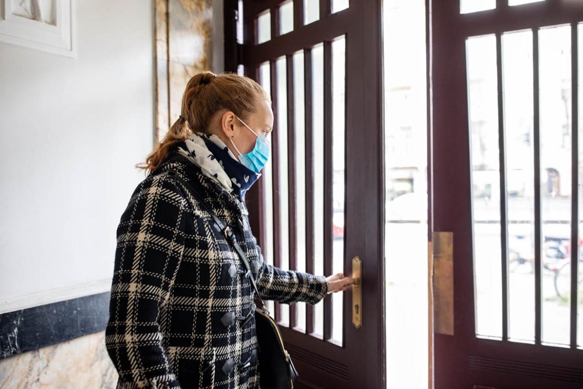 Woman in facemask opening door
