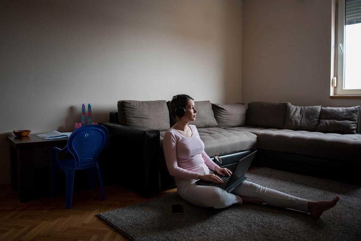 Woman sitting on floor alone with a laptop