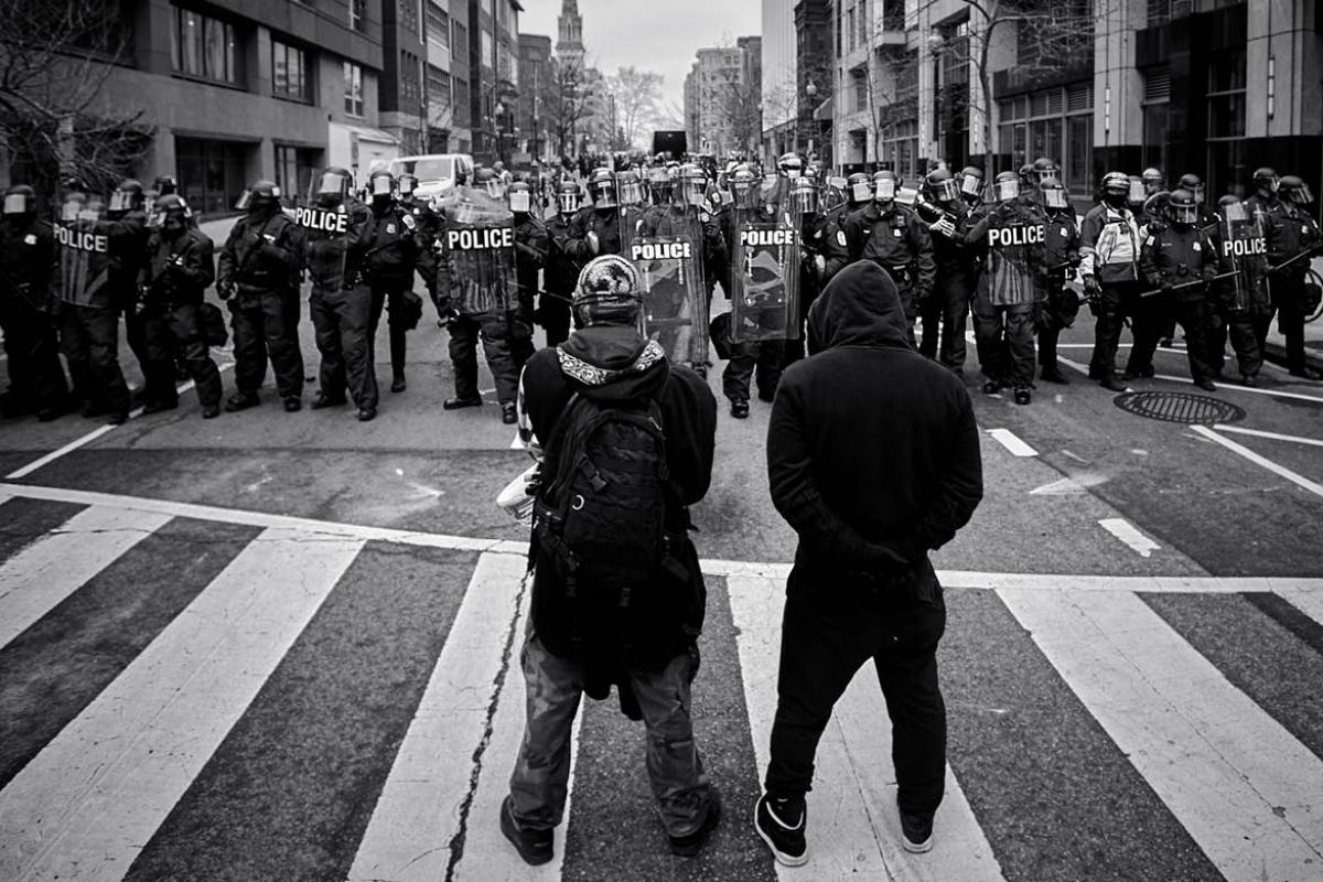 Two figures standing in front of law enforcement officers