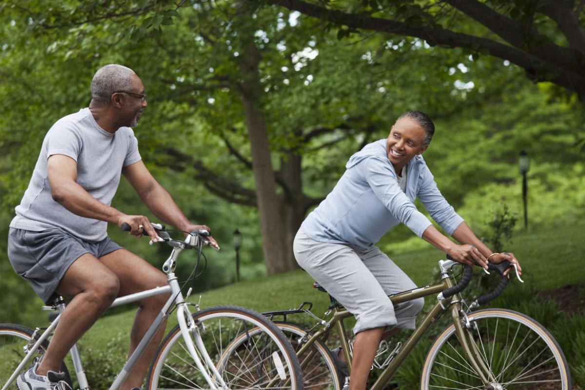 Two smiling people riding bikes