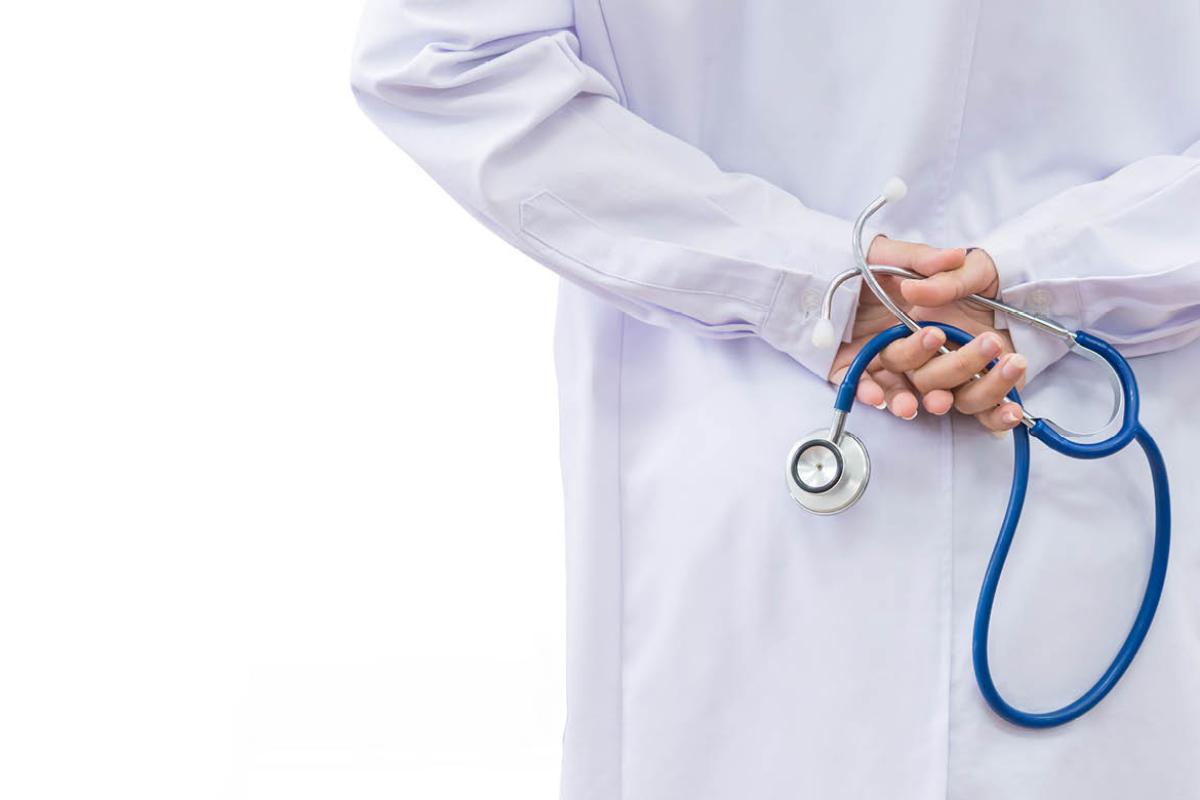 Physician holding stethoscope behind back