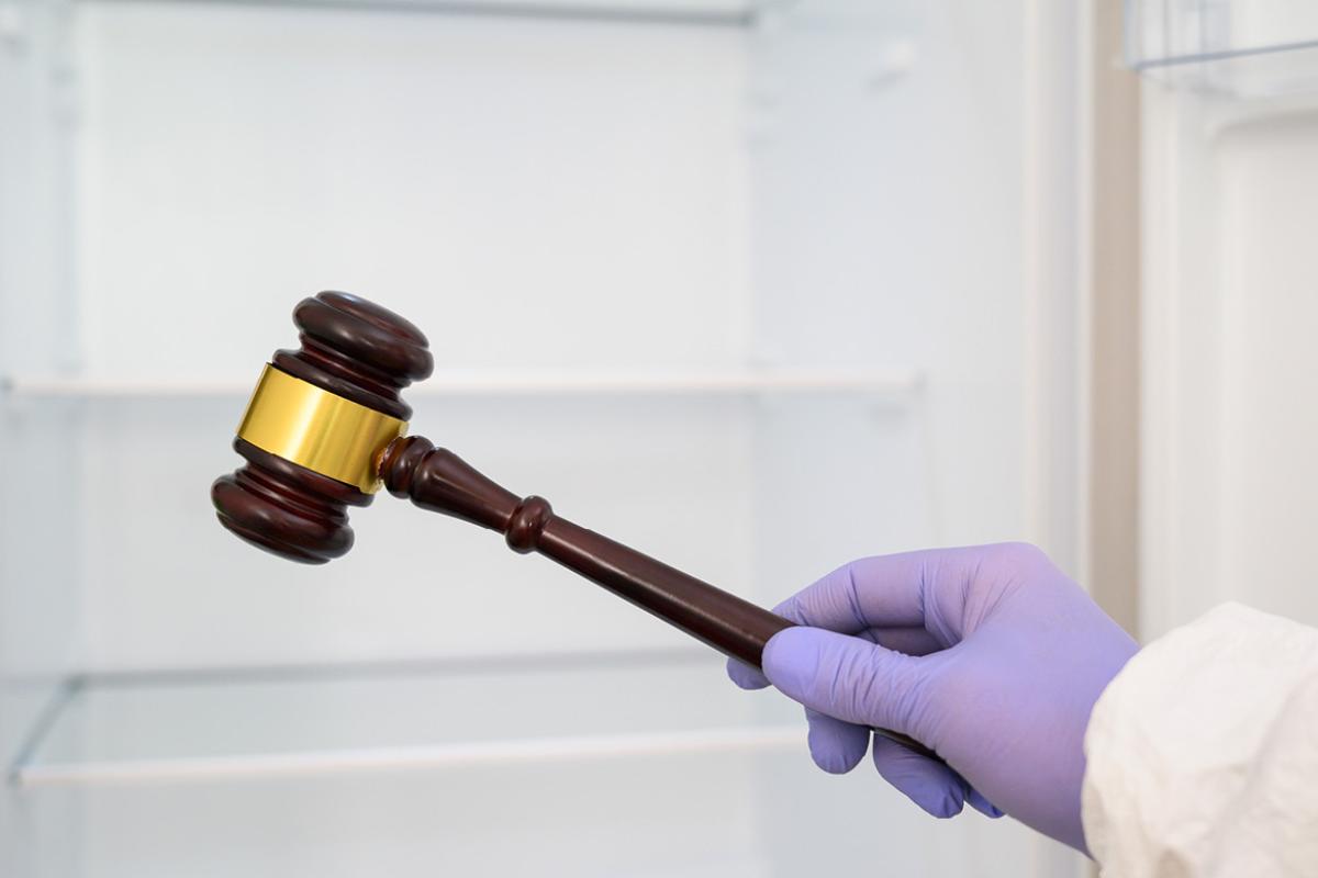 Gloved hand holding a court gavel.
