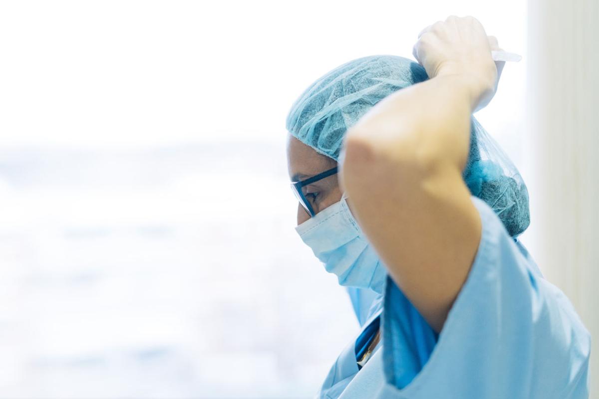 Health care professional tying mask around face