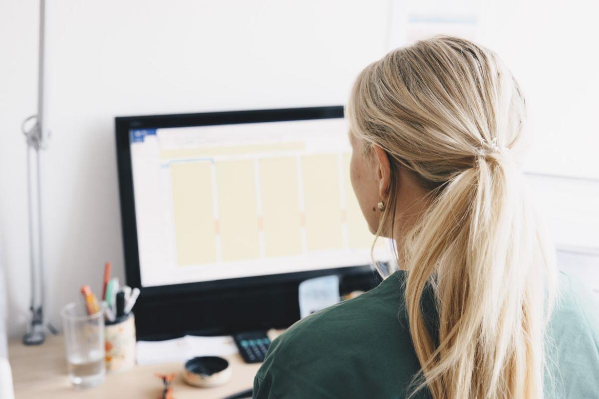 Tight shot of woman sitting at desk in front of computer screen.