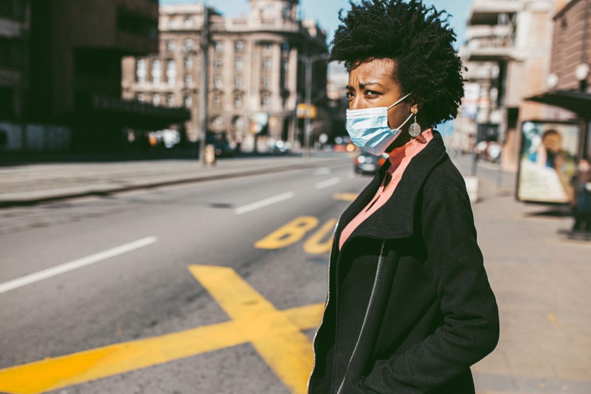 Person in a face mask standing by a street