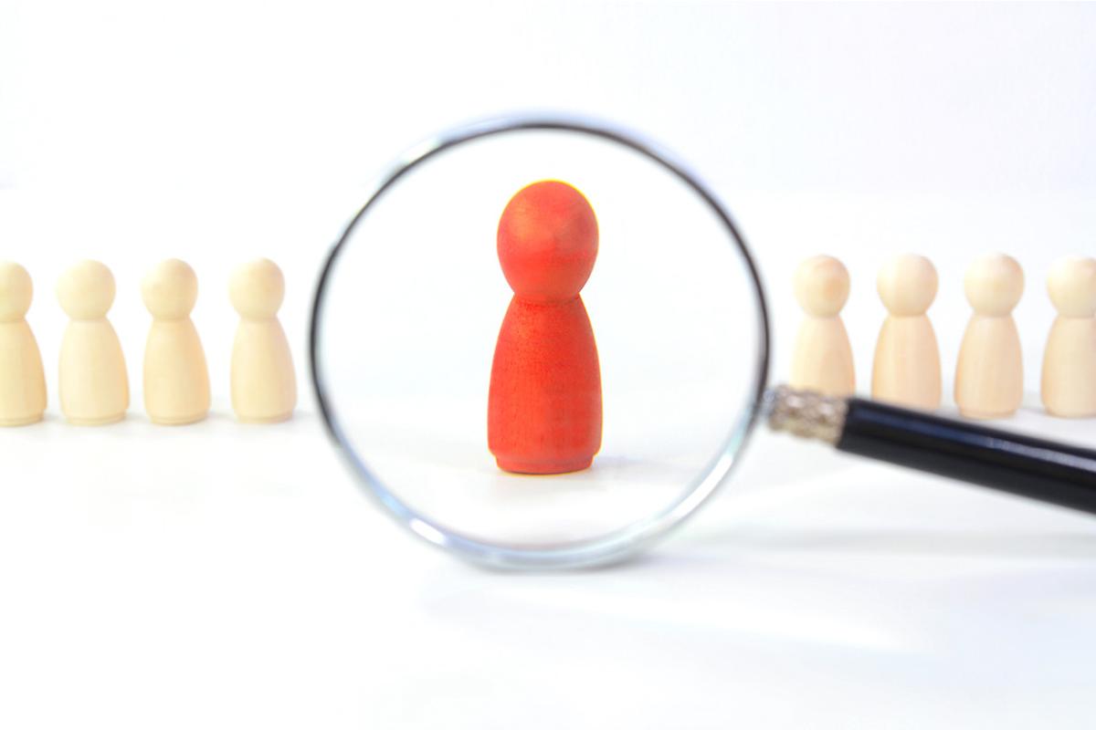 Illustration of a magnifying glass looking at beige game pieces with the focus on a single red game piece
