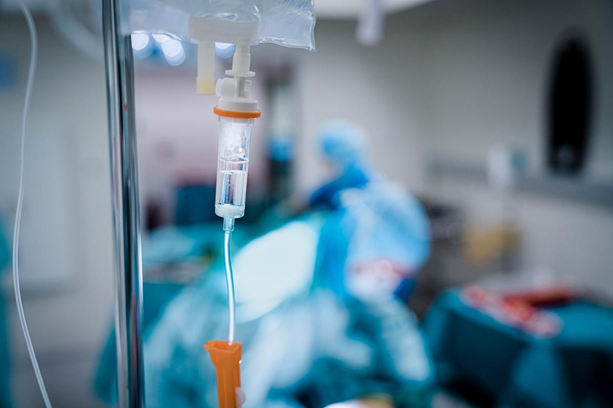 Close-up of an intravenous drip with physicians working in the background