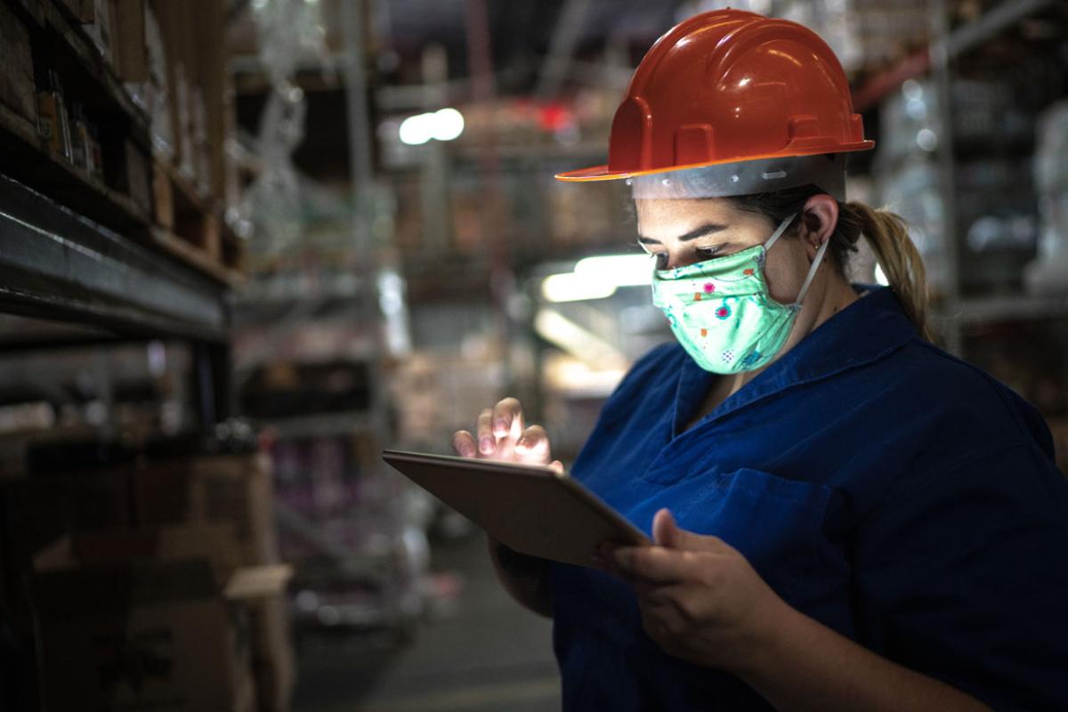 Warehouse worker wearing a face mask checking a smartpad.